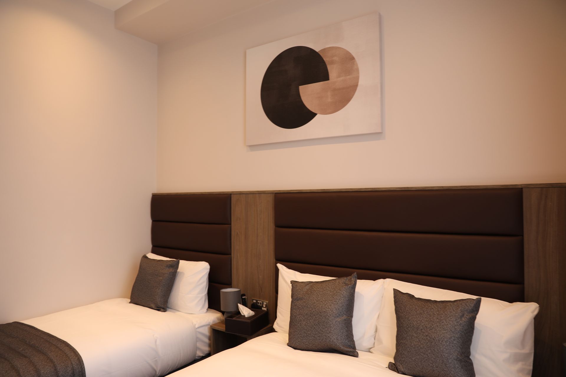 A hotel room with two beds and a painting on the wall.