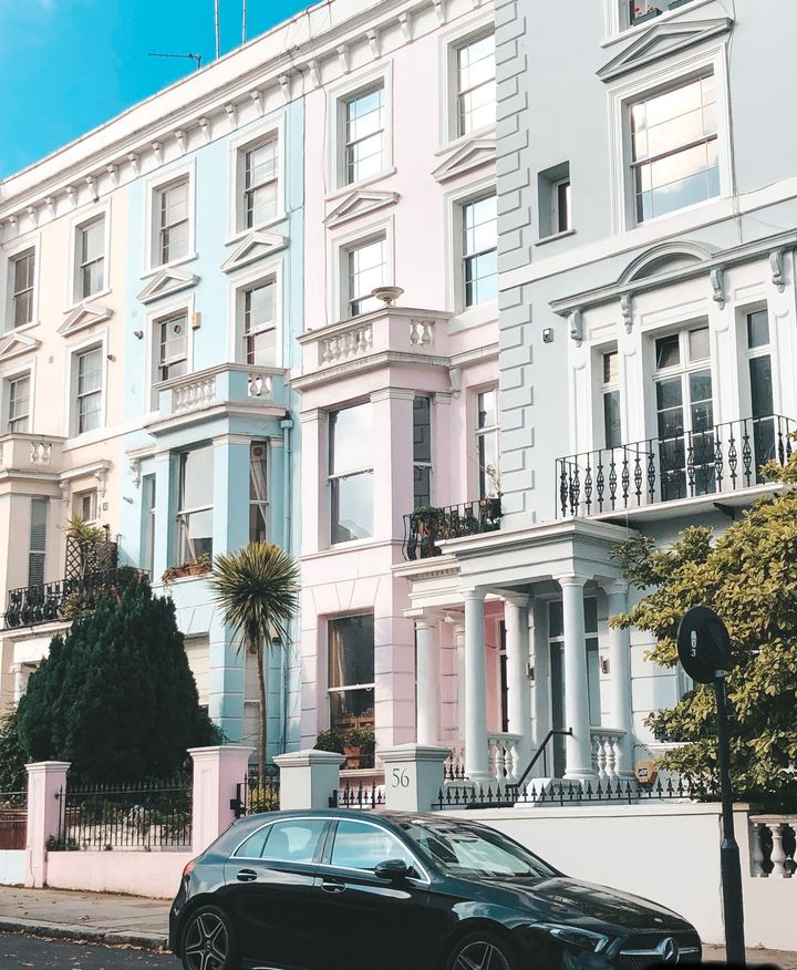 A black car is parked in front of a row of buildings.