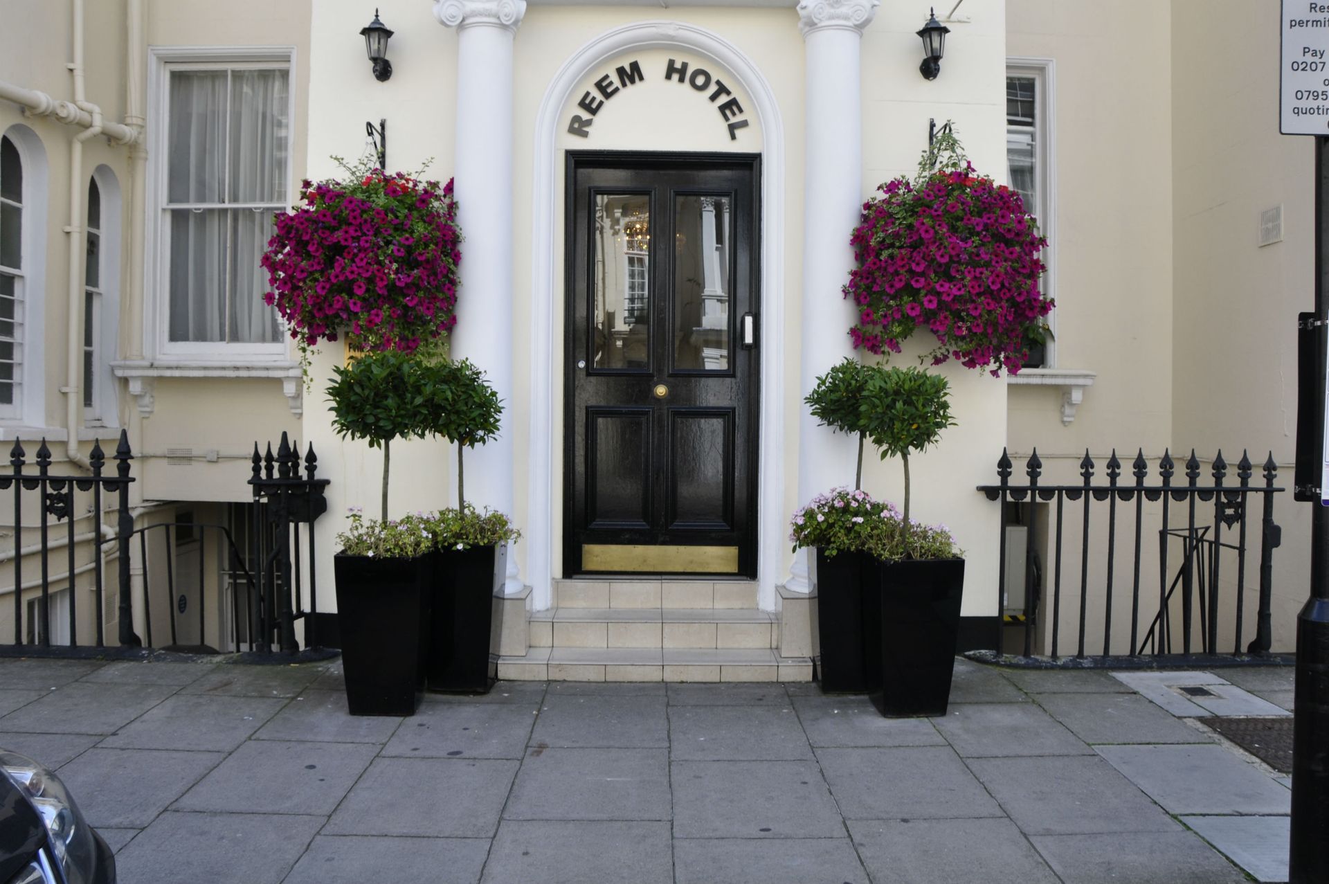 A white building with a black door that says reem hotel