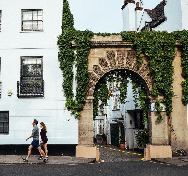 A couple walking in front of a building with a stone archway