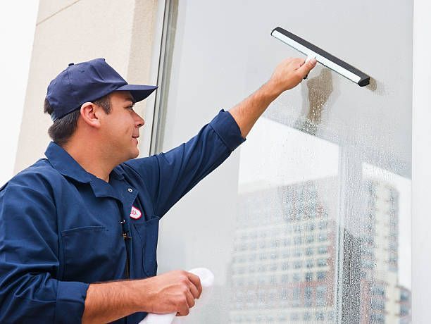A Man Is Cleaning A Window With A Squeegee — Cheyenne, WY — Top Mop C.