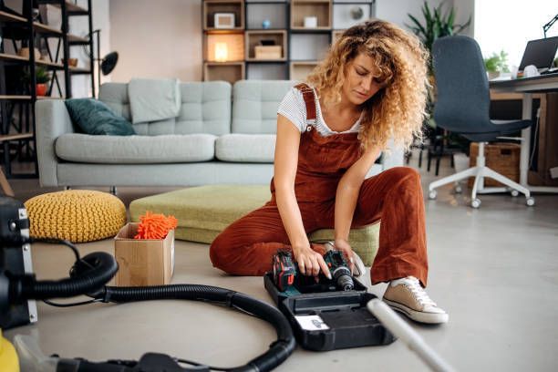 A Woman Is Cleaning The Floor With A Vacuum Cleaner In A Living Room — Cheyenne, WY — Top Mop C.
