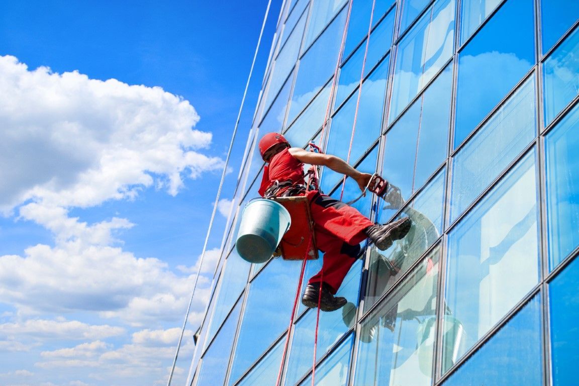 A man is cleaning the windows of a tall building.