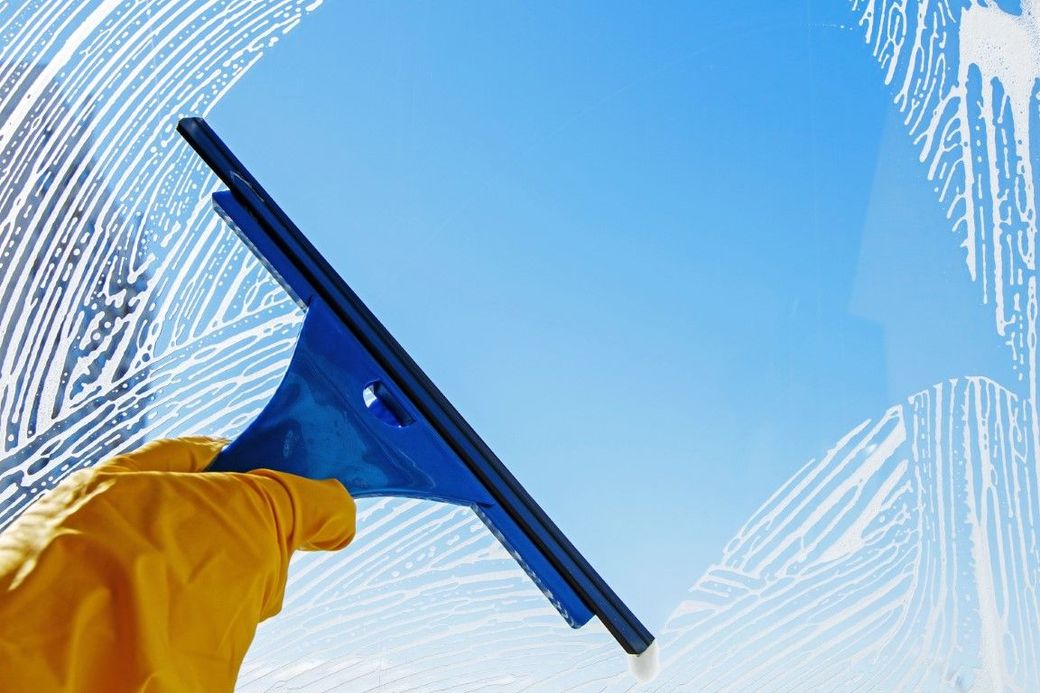 A person is cleaning a window with a squeegee.