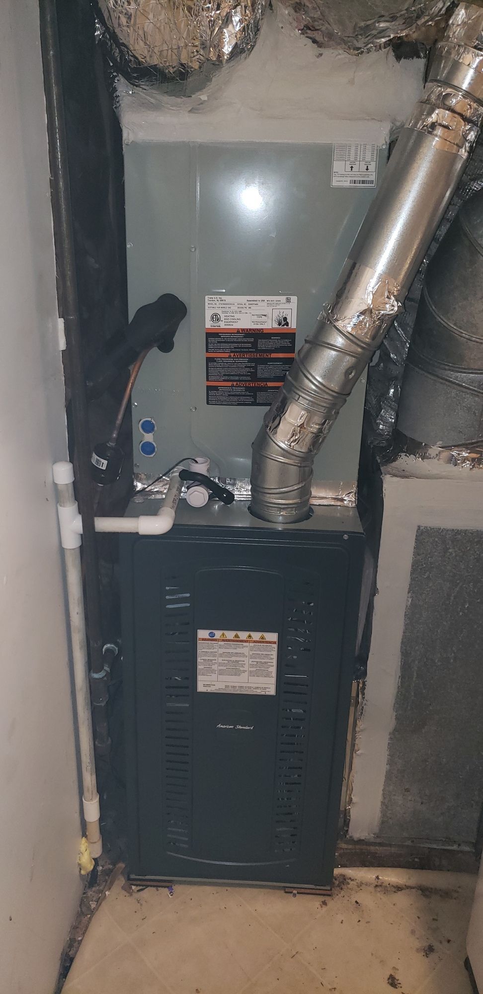 A furnace is sitting in the corner of a room in a house.