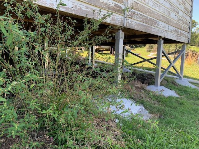 A wooden house is sitting on stilts in the grass.