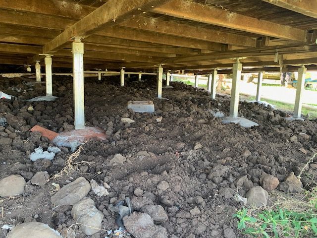 A pile of dirt and rocks under a house.