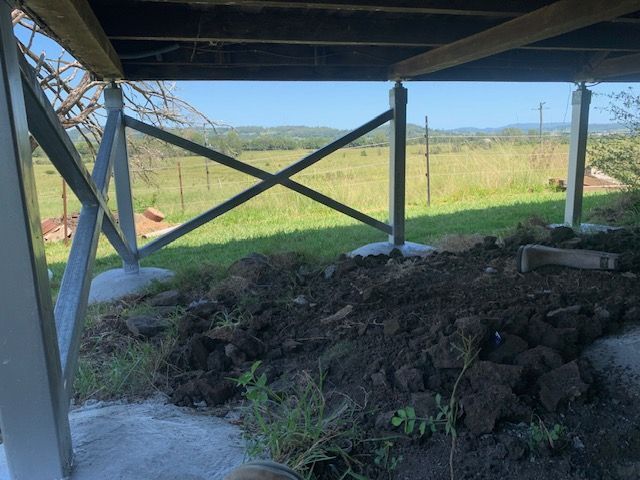 A pile of dirt is sitting under a wooden structure in a field.