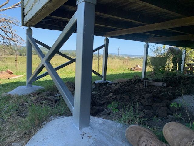 A person is laying on the ground under a house.