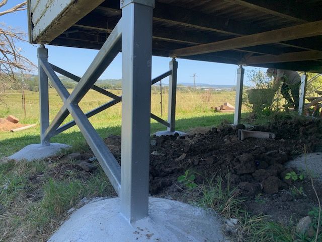 A man is digging in the dirt under a house.
