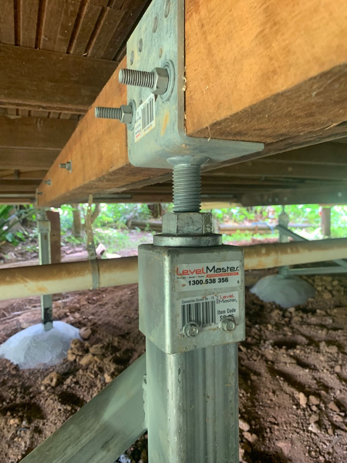 A close up of a metal post under a wooden deck.