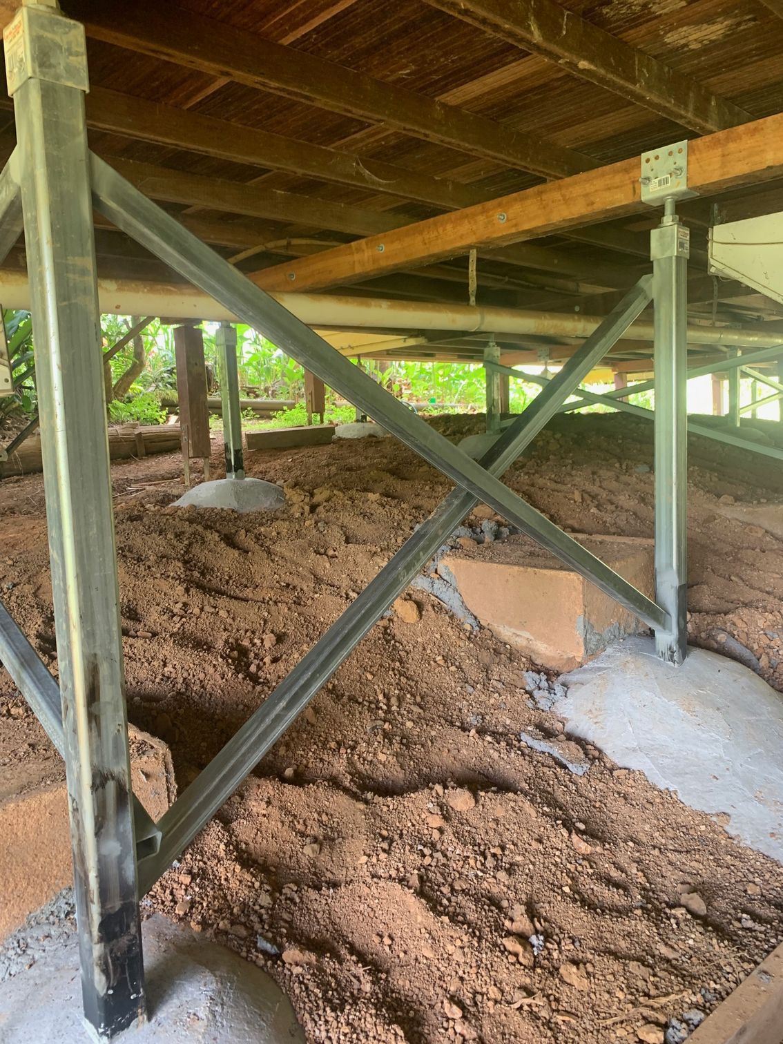 The underside of a house with a lot of dirt underneath it.