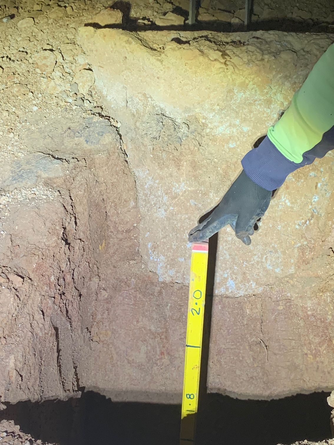 A person is measuring a rock with a yellow ruler