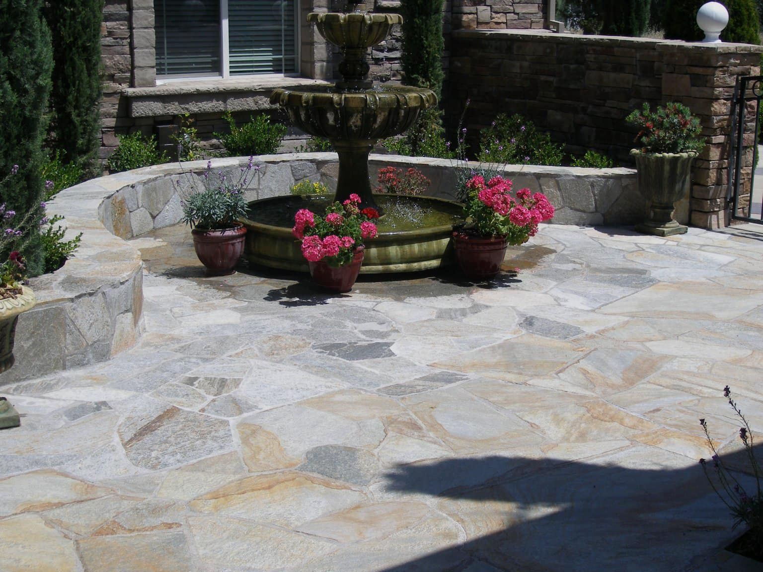 A stone patio with a fountain and potted plants