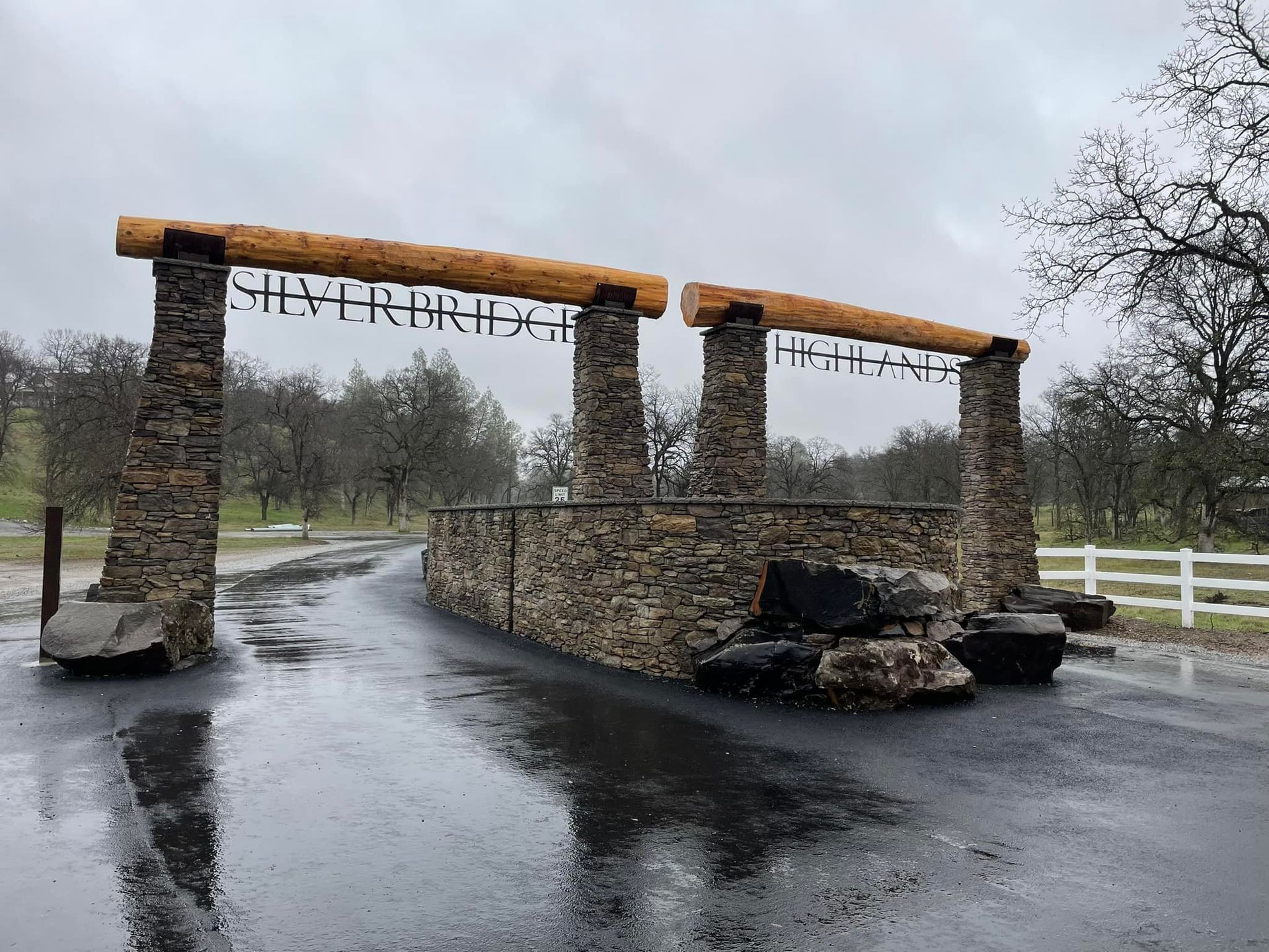 A stone archway over a road with a wooden sign above it.