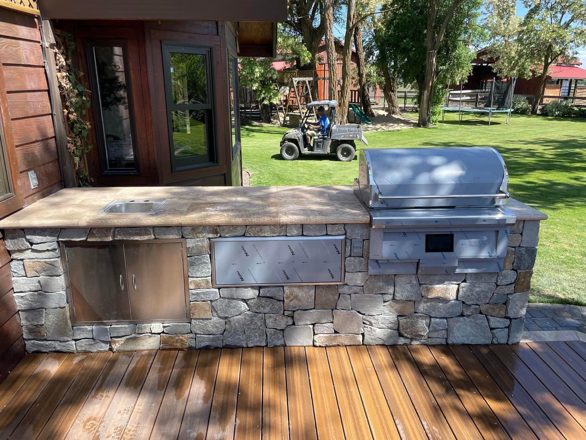 A grill is sitting on top of a wooden deck next to a golf cart.
