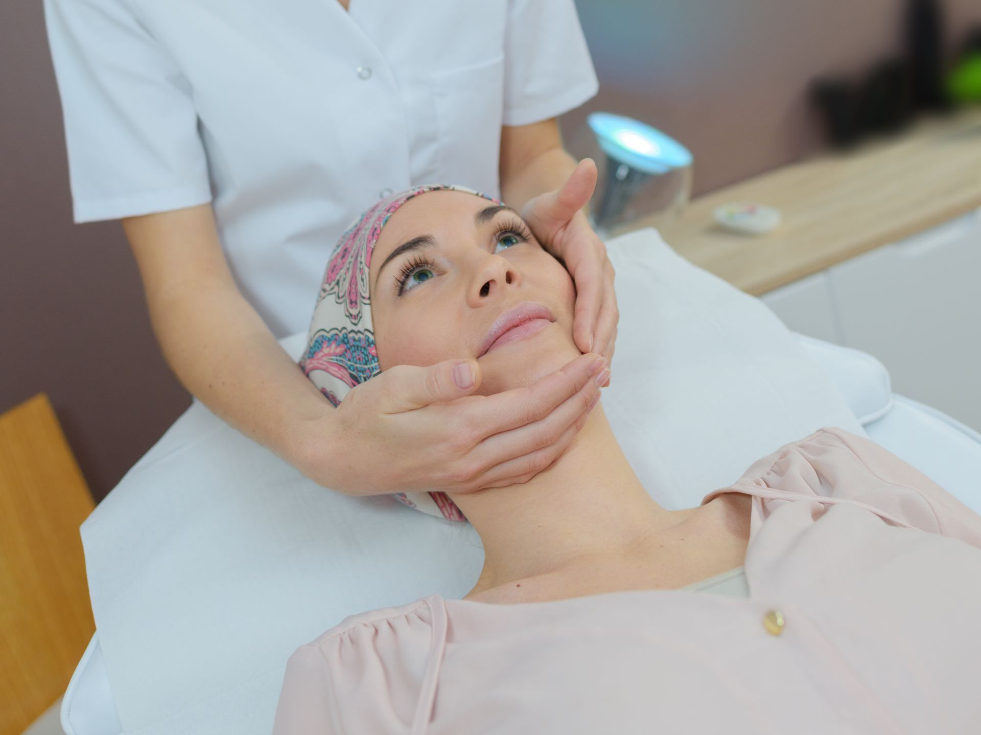 a woman with a scarf on her head is getting a facial massage