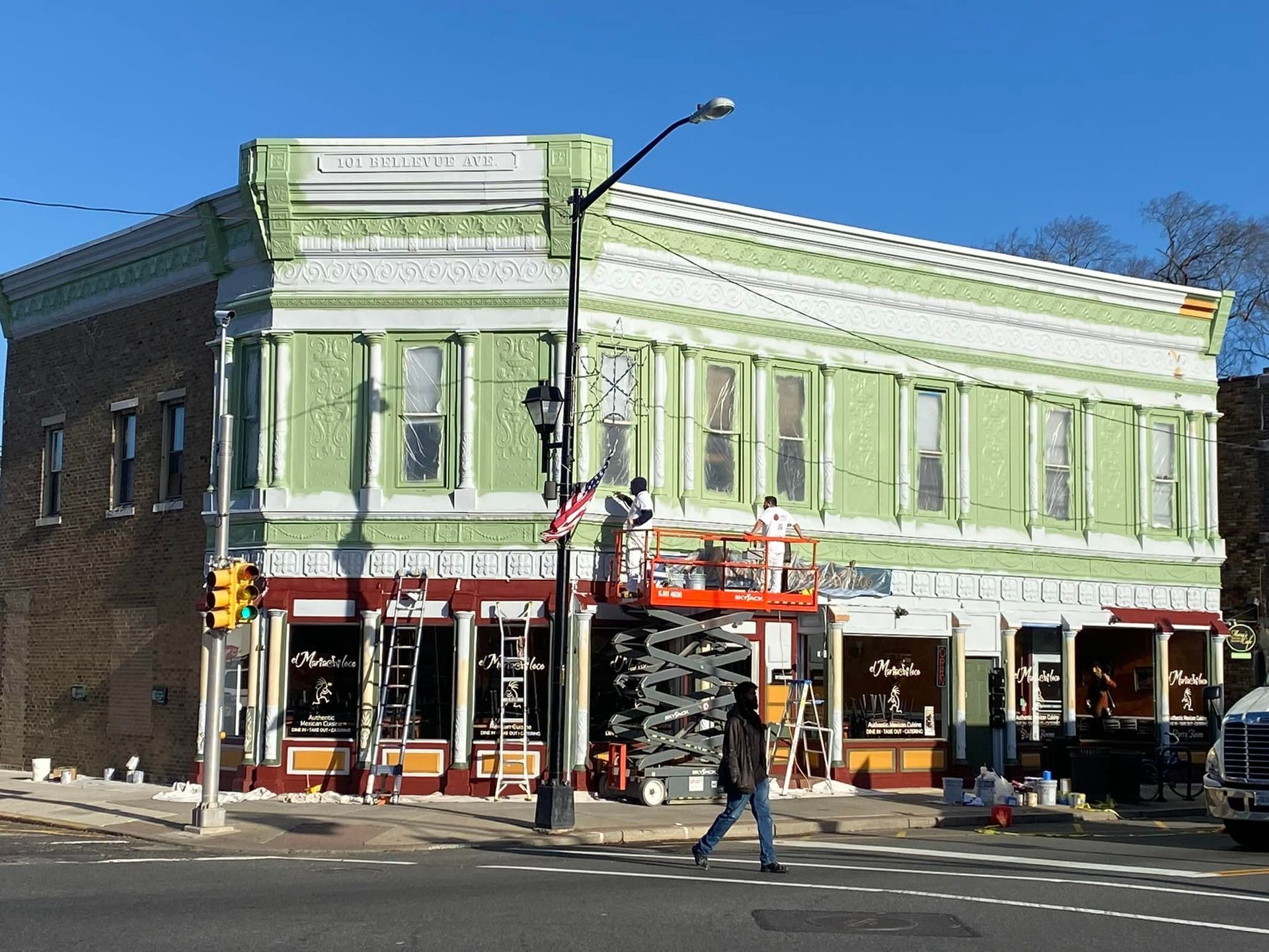 A green building is being painted on the corner of a street