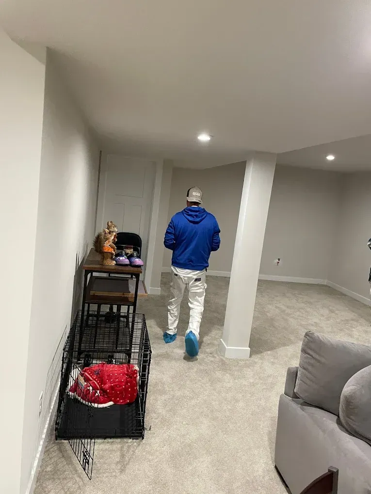 A man is walking through a living room in a basement.