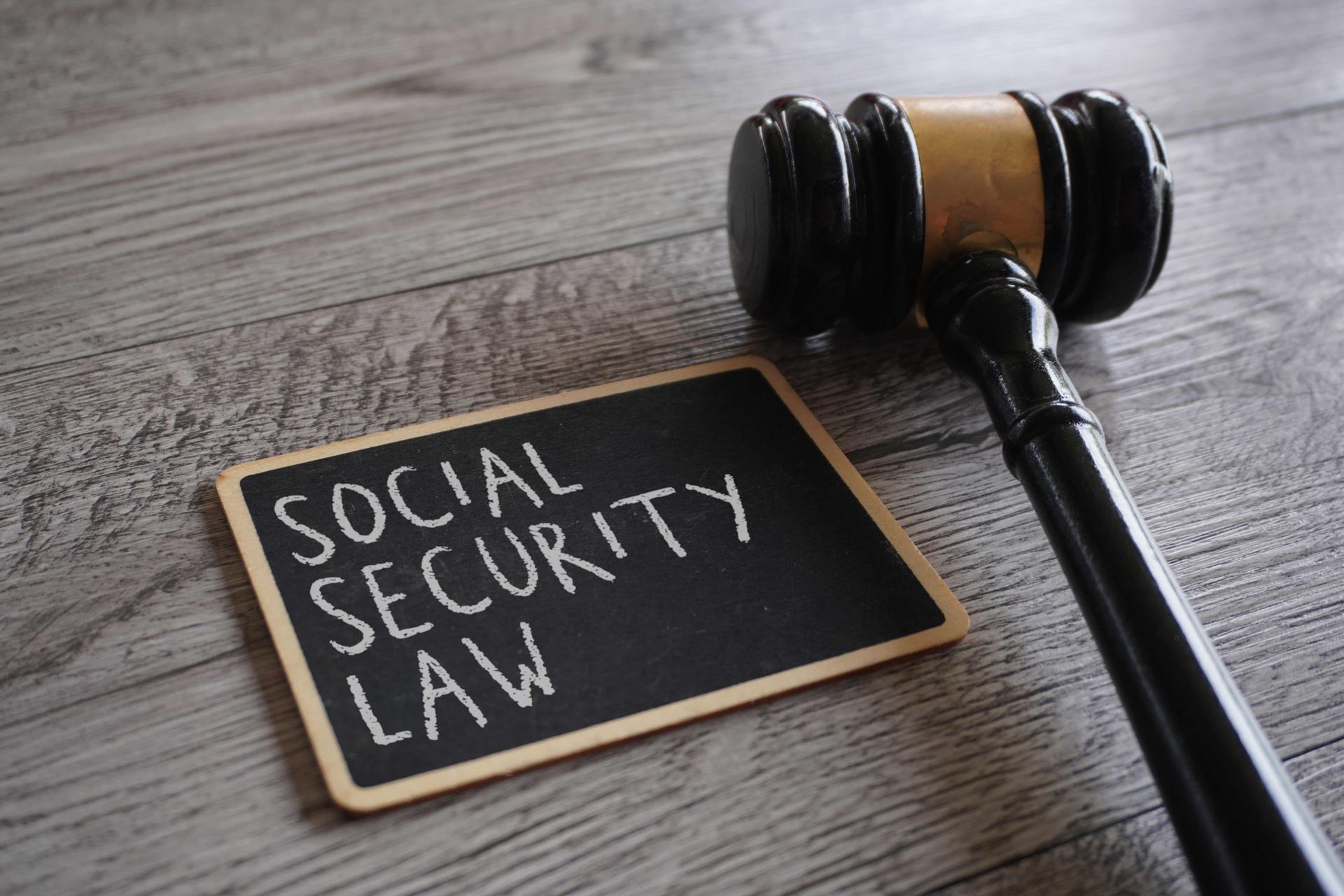 social security disability lawyer gavel and chalkboard with Social Security Law text on desk.