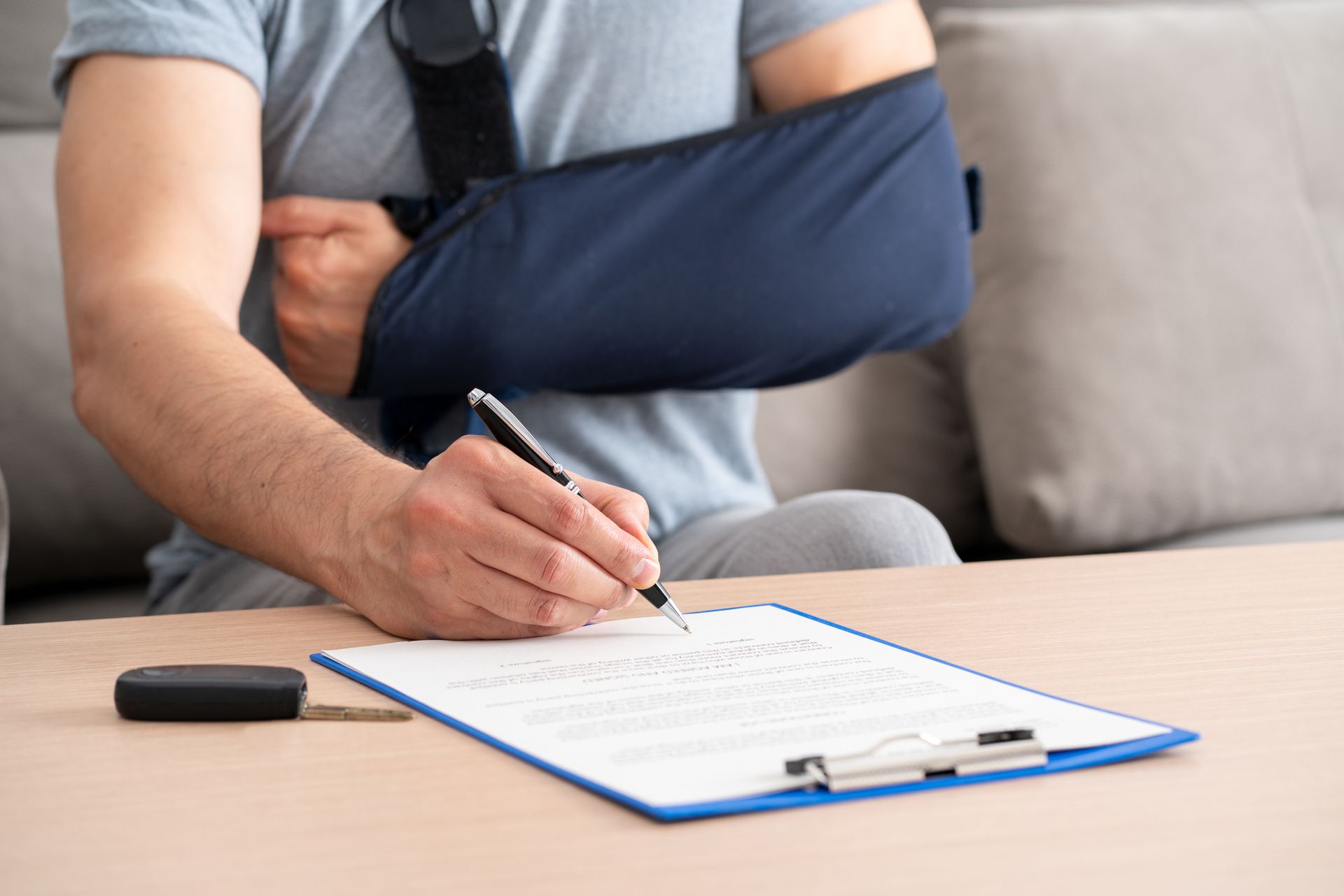 A close-up of a man with a broken arm in a sling signing a SSD document.