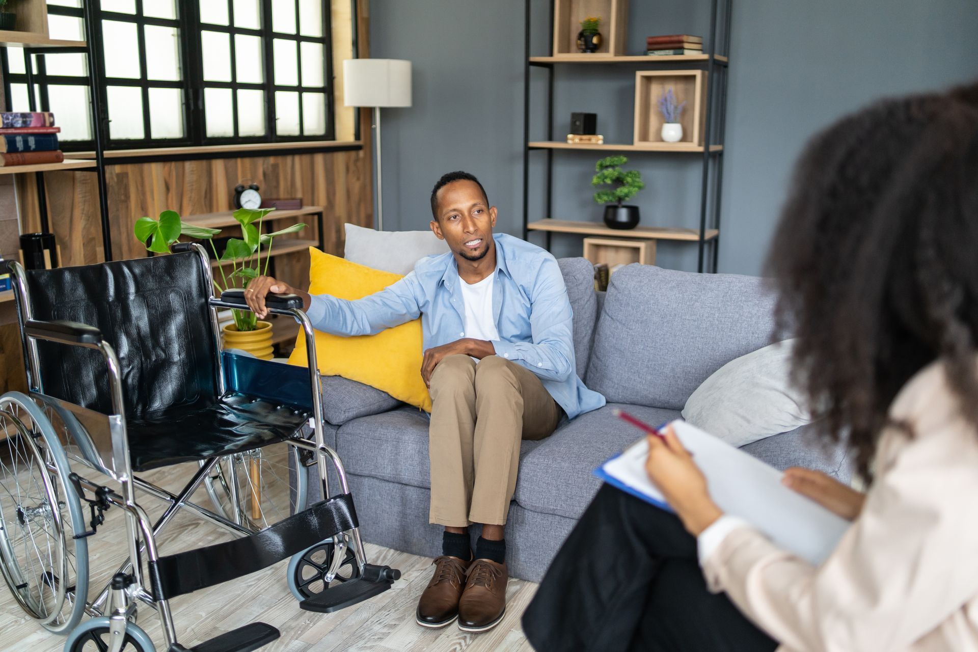 A man sitting next to a wheelchair is receiving professional help from a female lawyer in an office.