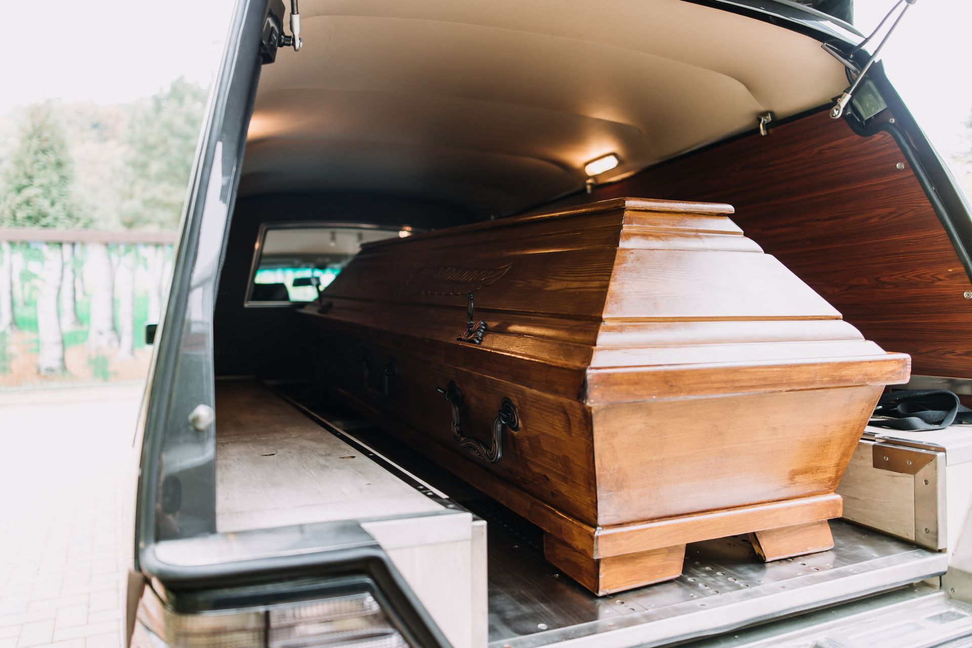 Wooden coffin in the back of a hearse with the rear hatch open