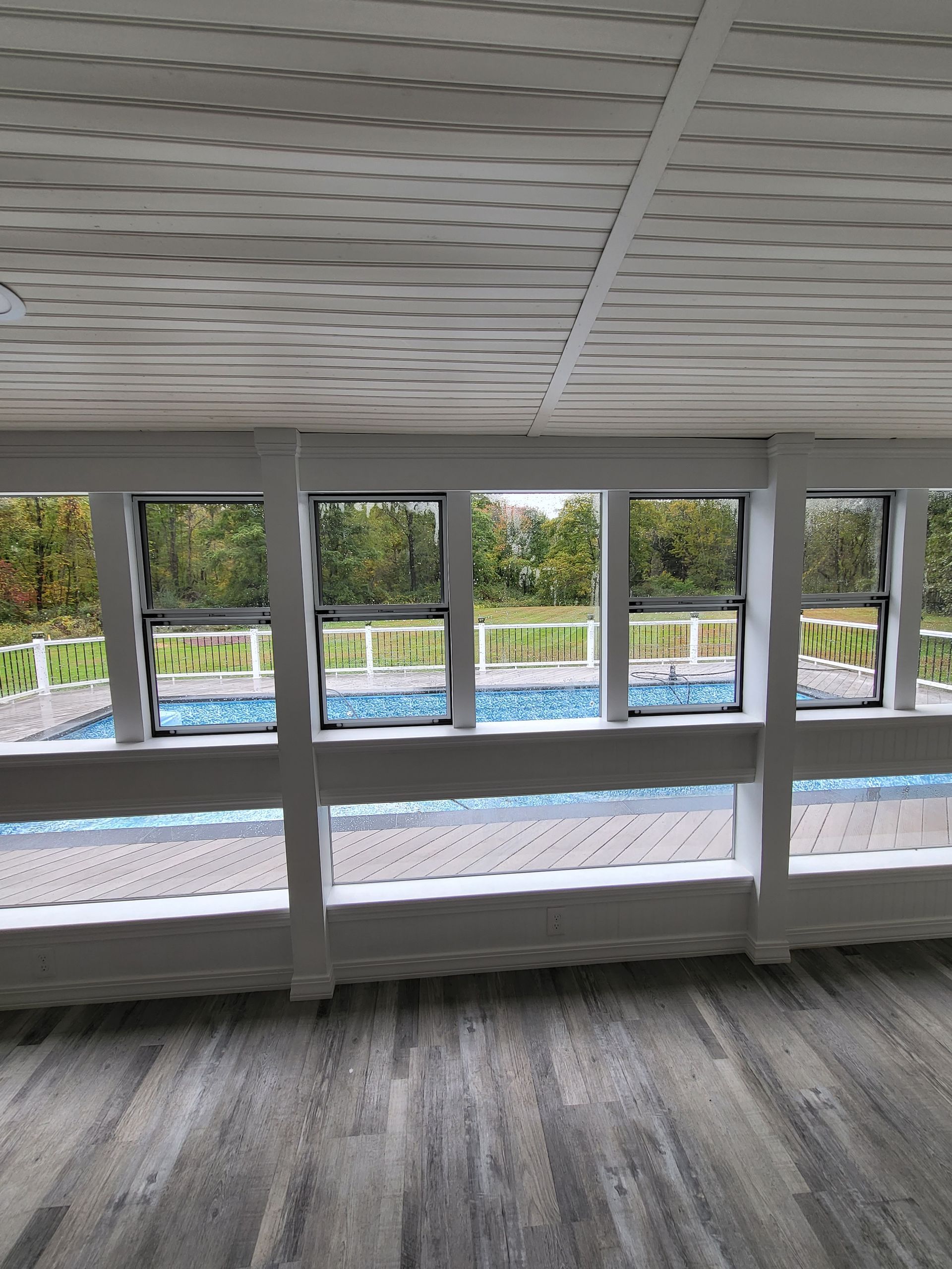 A room with a lot of windows and a pool in the background