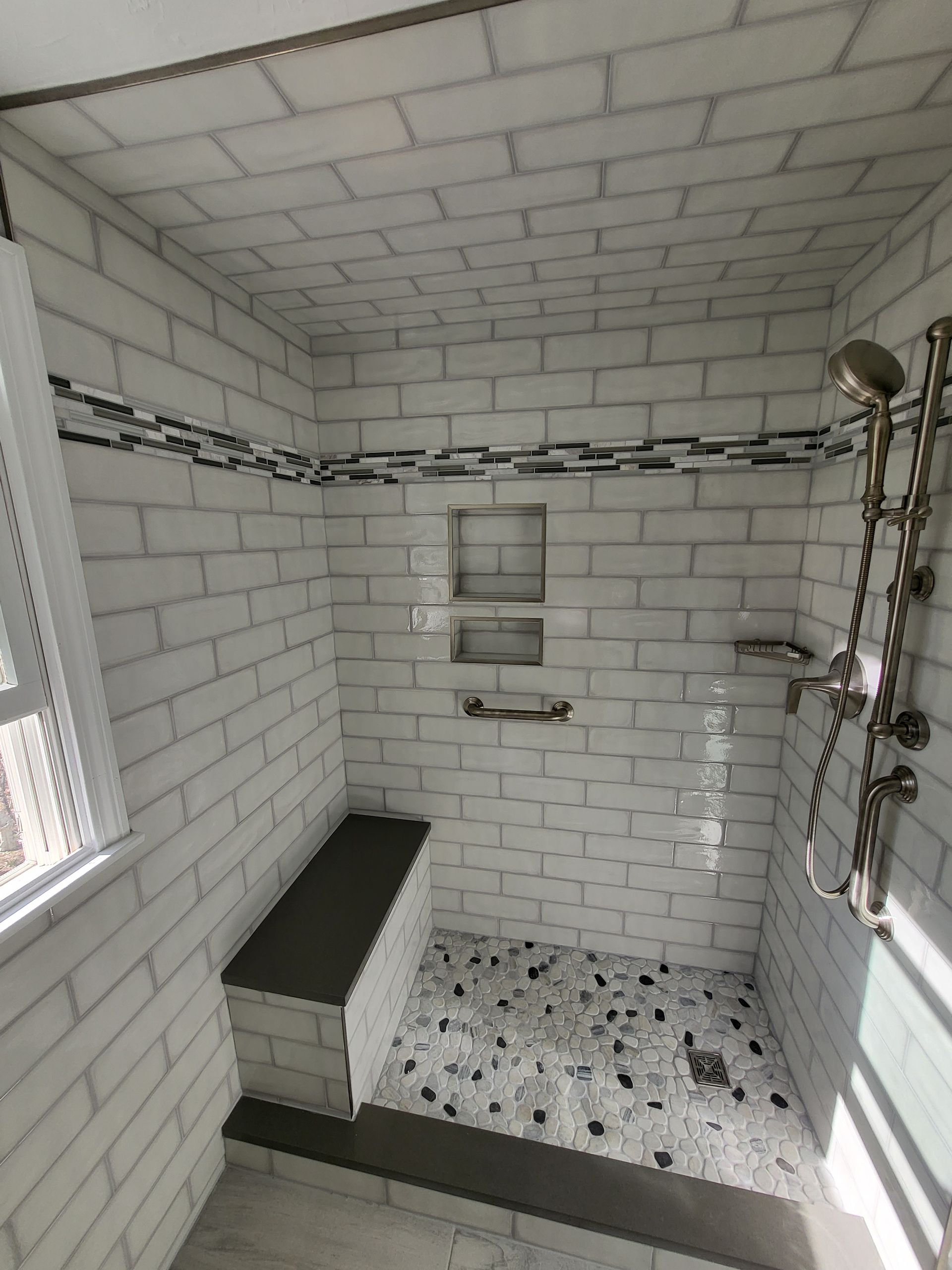 A bathroom with white brick walls and a walk in shower.