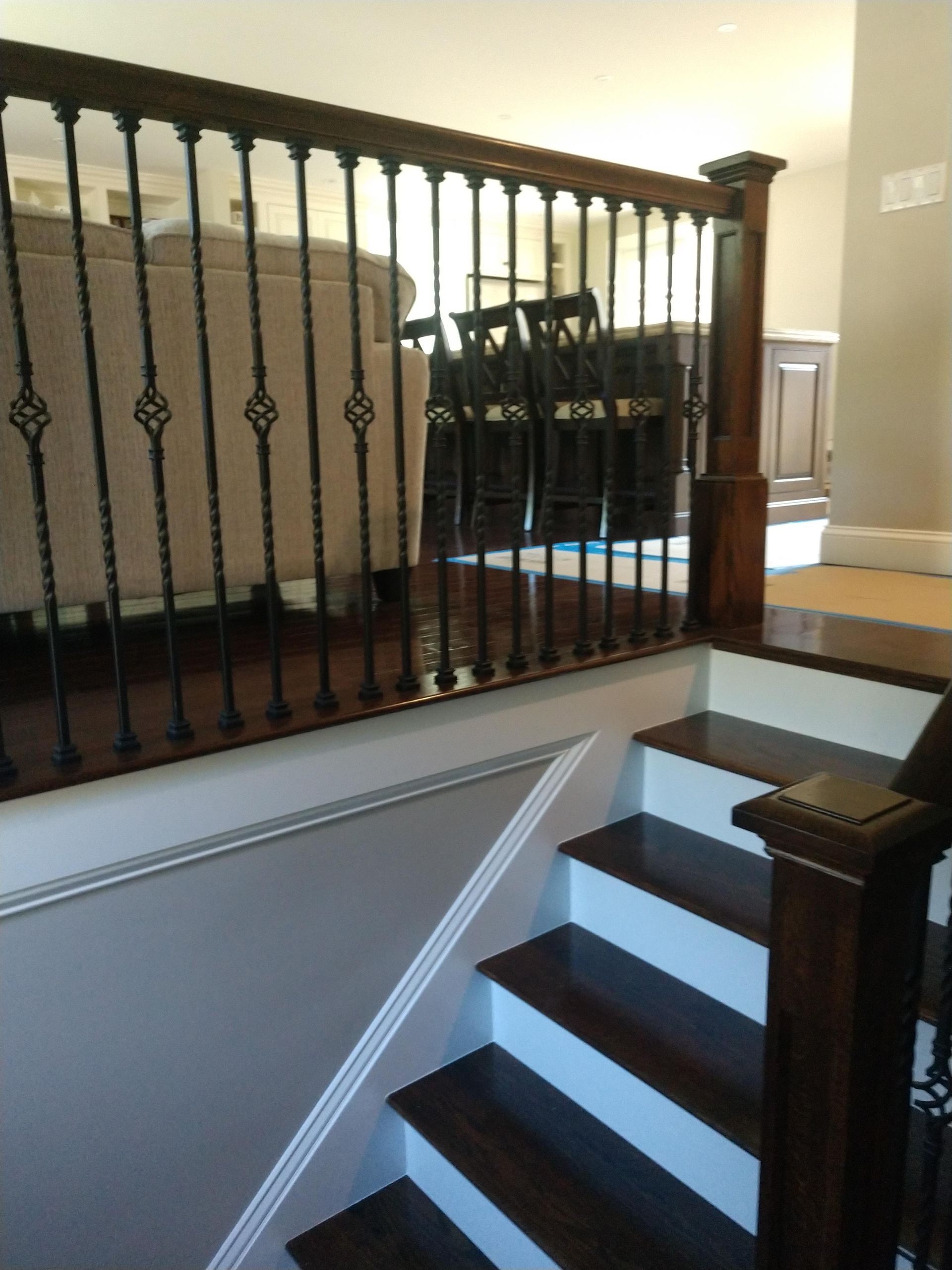 A staircase leading up to a living room with a wrought iron railing