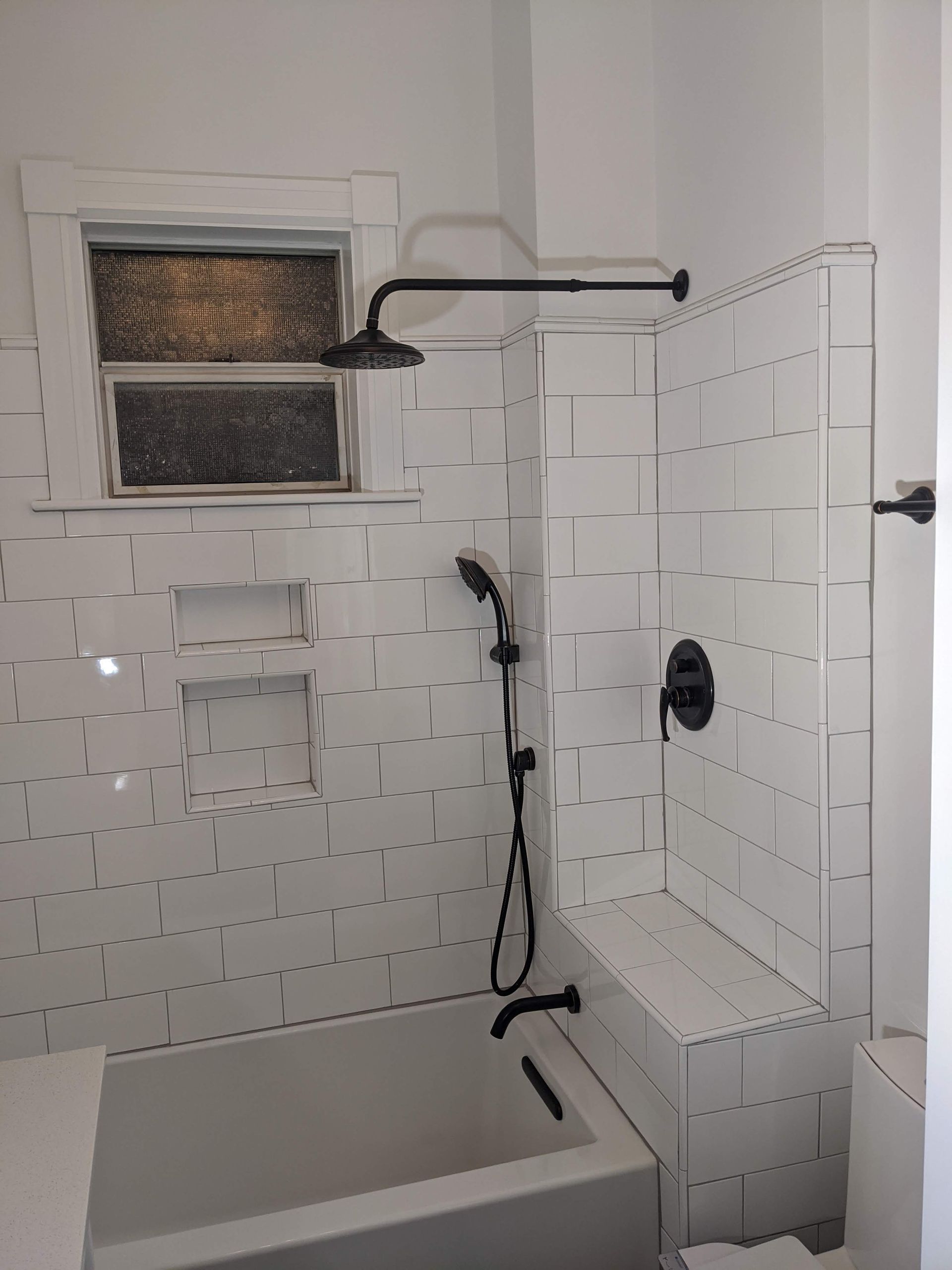 A bathroom with a bathtub , shower , toilet and window.