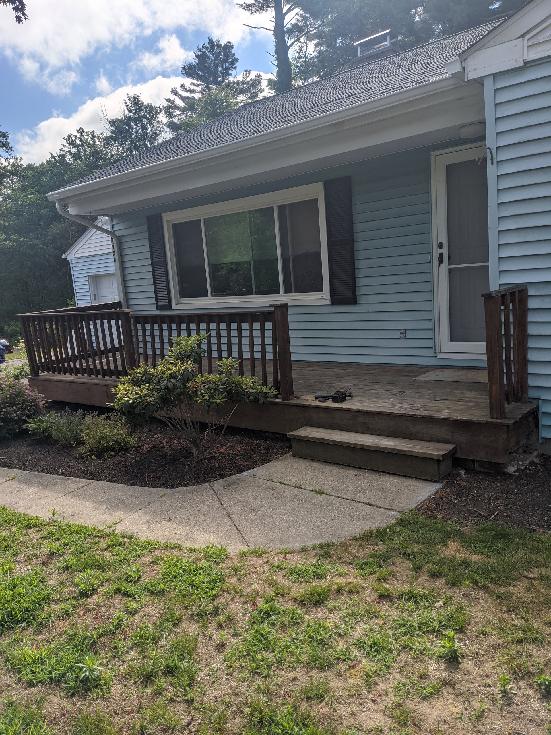 A blue house with a porch and a sliding glass door.