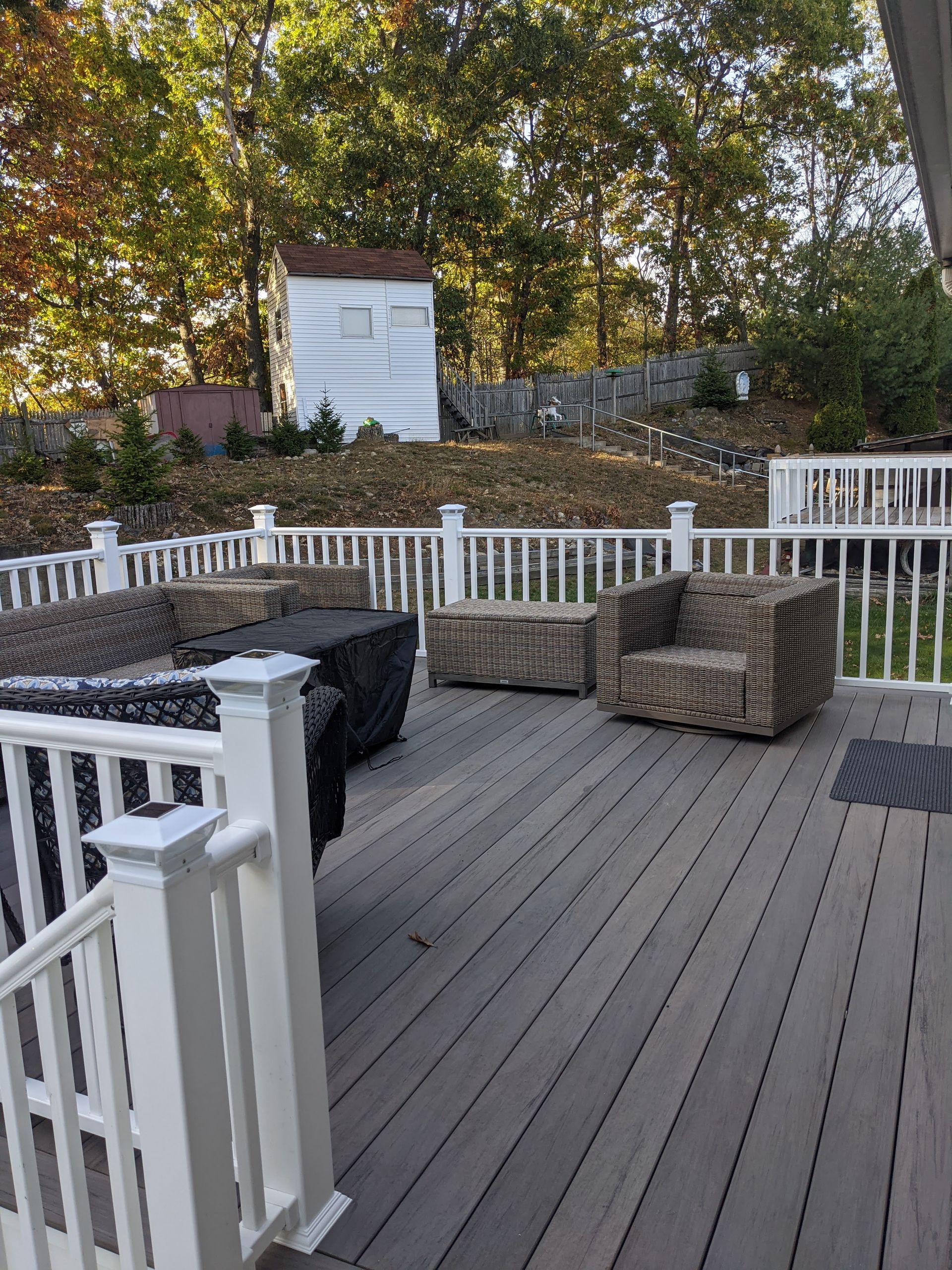 A deck with a white railing and a couch and chairs on it.
