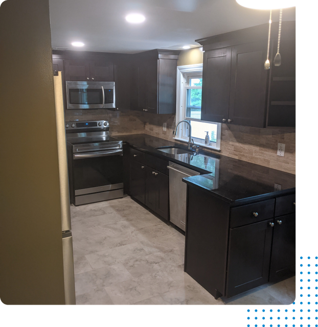 A kitchen with black cabinets and stainless steel appliances