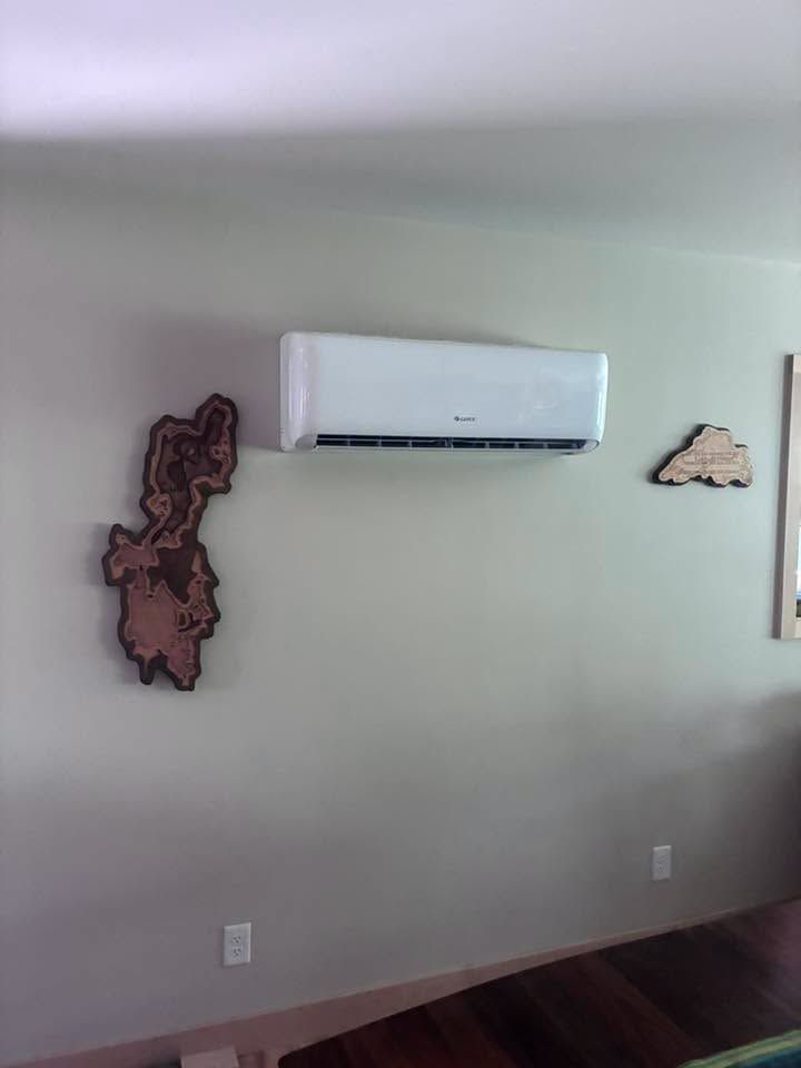 Empty room wall with a white wall-mounted air conditioner and decorative wall art.