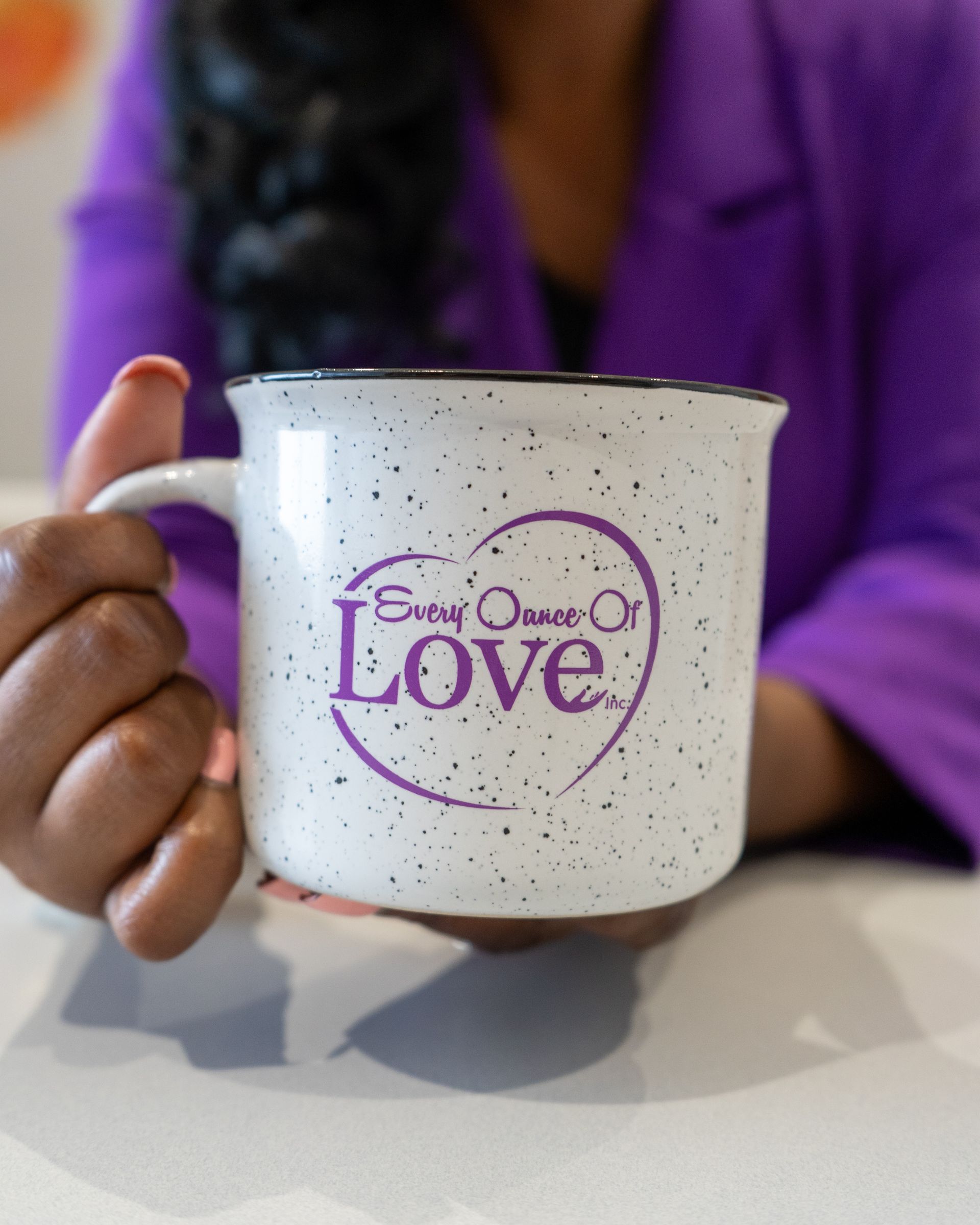 Person holding a speckled white mug with 