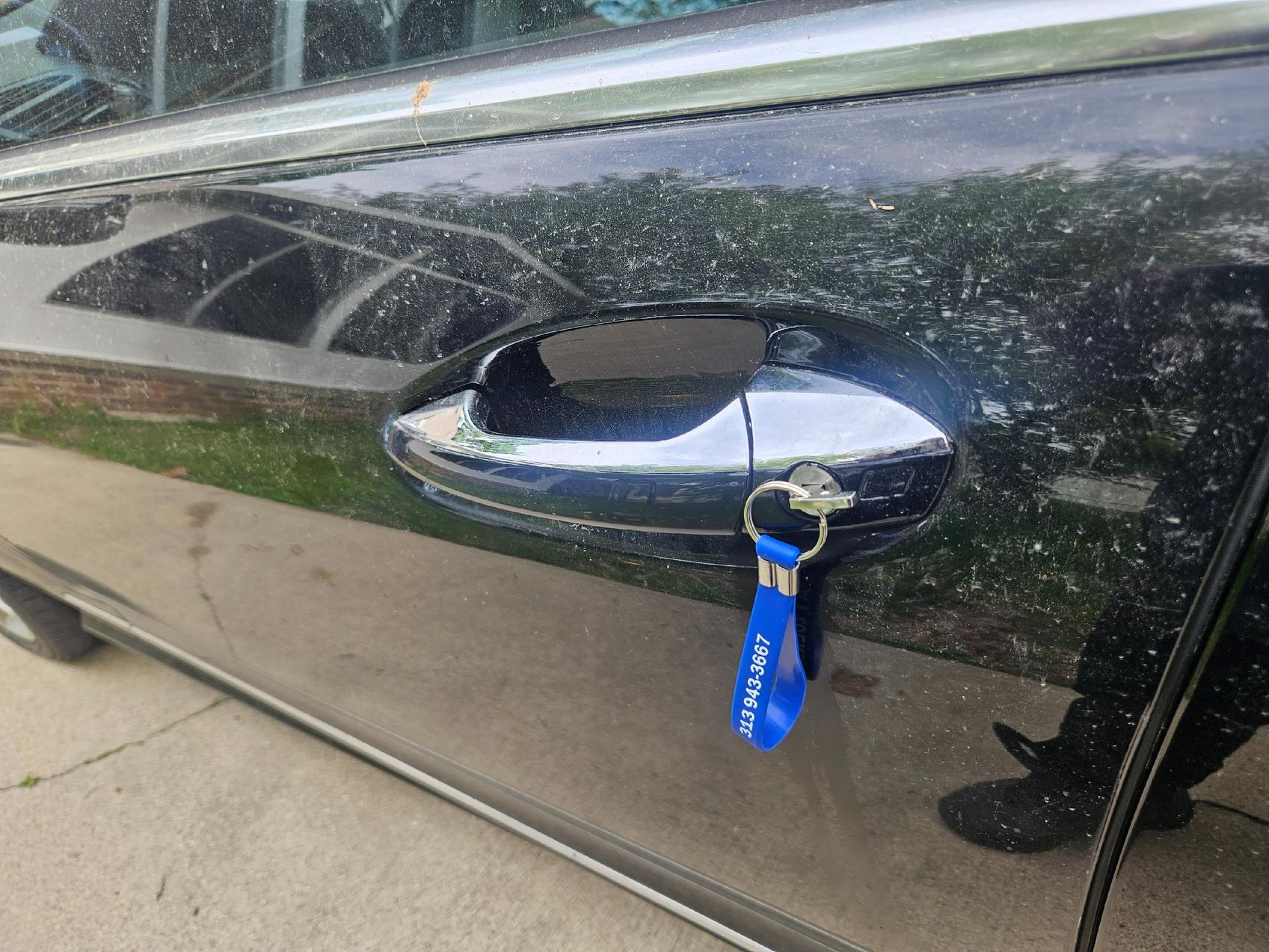 Black car door with keys in the handle, blue lanyard.