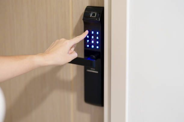 Person's finger pressing numbers on a smart door lock with a keypad and fingerprint reader.