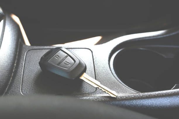 Car key with two buttons rests on a console next to a cup holder.