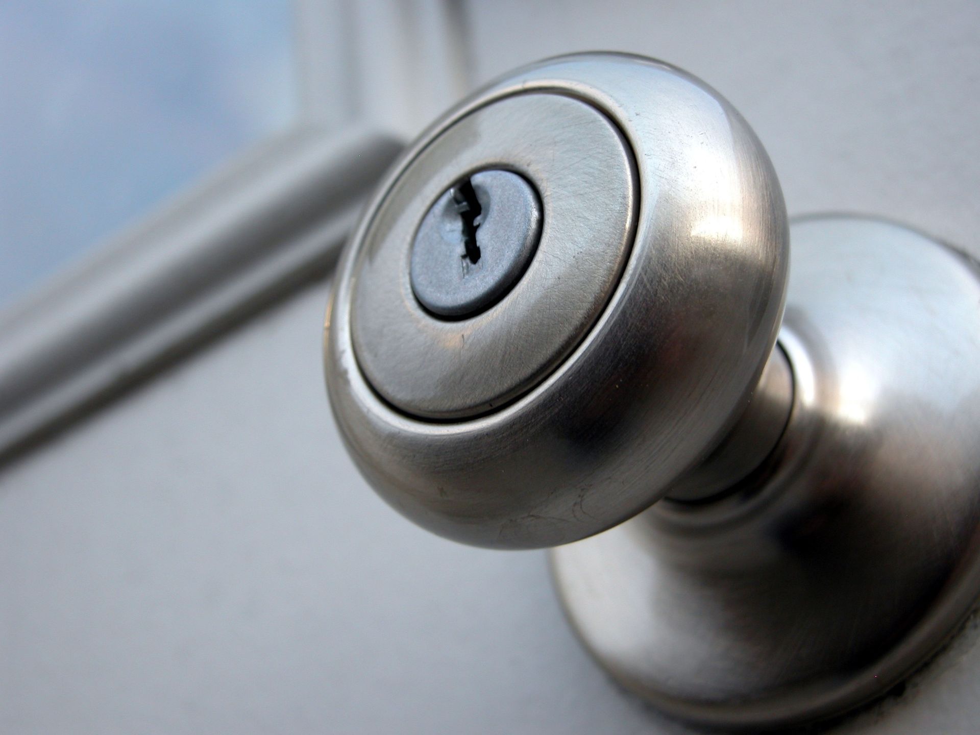 Silver doorknob on a white door, close-up view showing the keyhole.