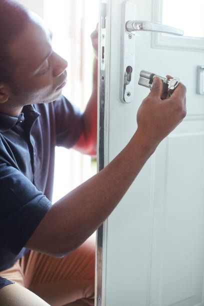 Person installing a lock on a white door.