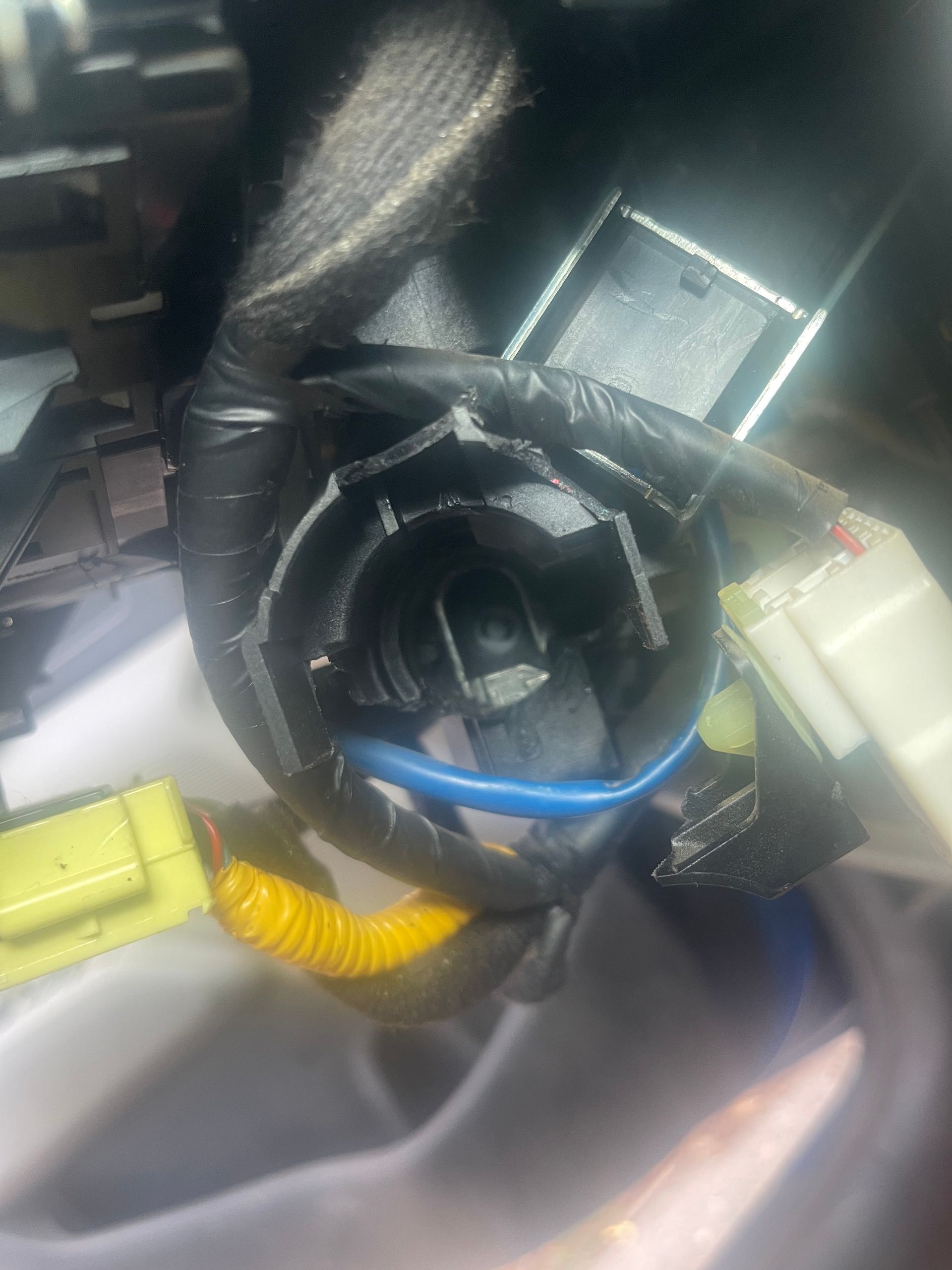 Close-up of a damaged car ignition switch, surrounded by wires and electrical connectors.