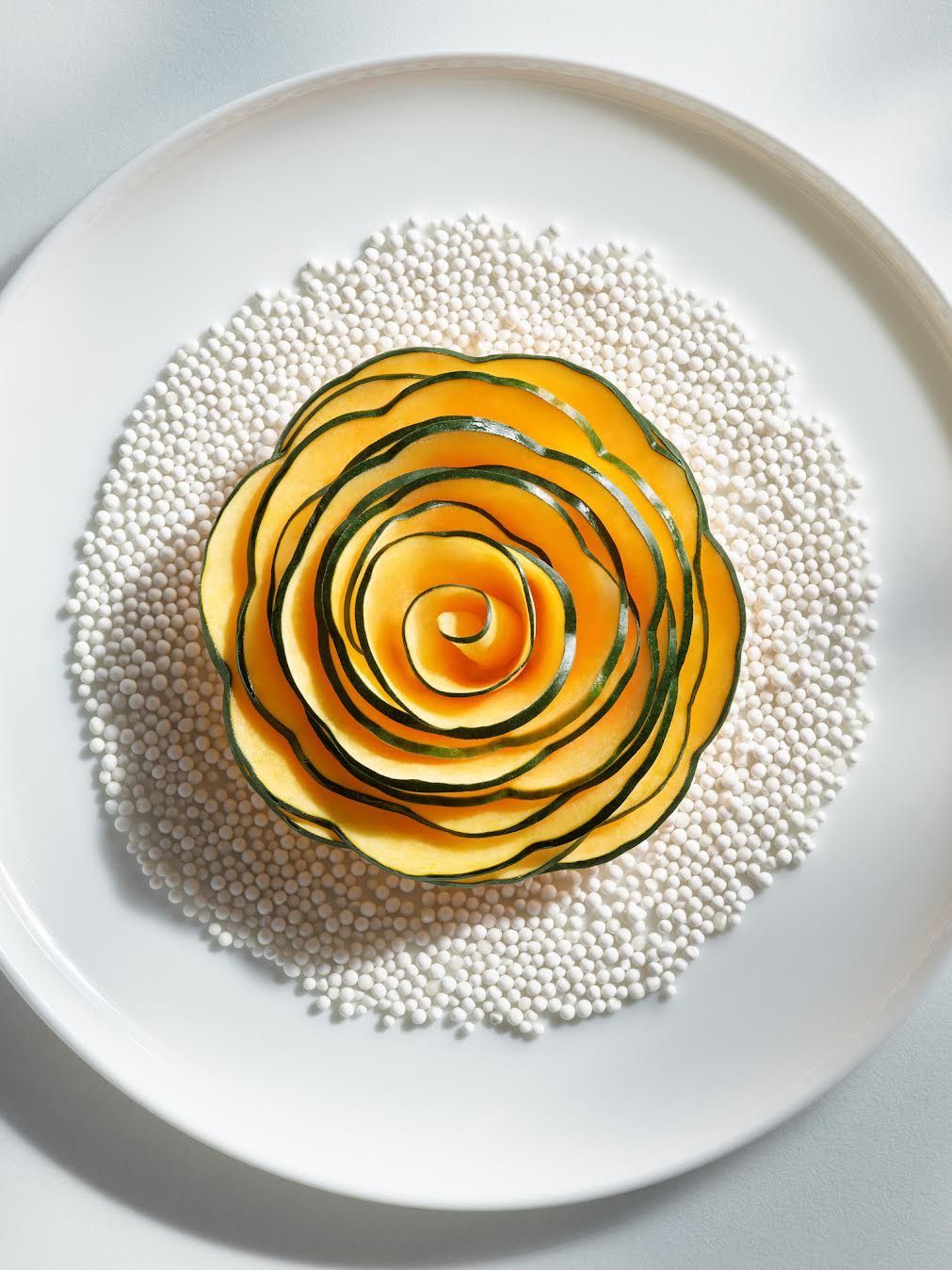 Yellow rose made from fruit, ringed by white tapioca pearls, on a white plate. Food Stylist Nadine Page.