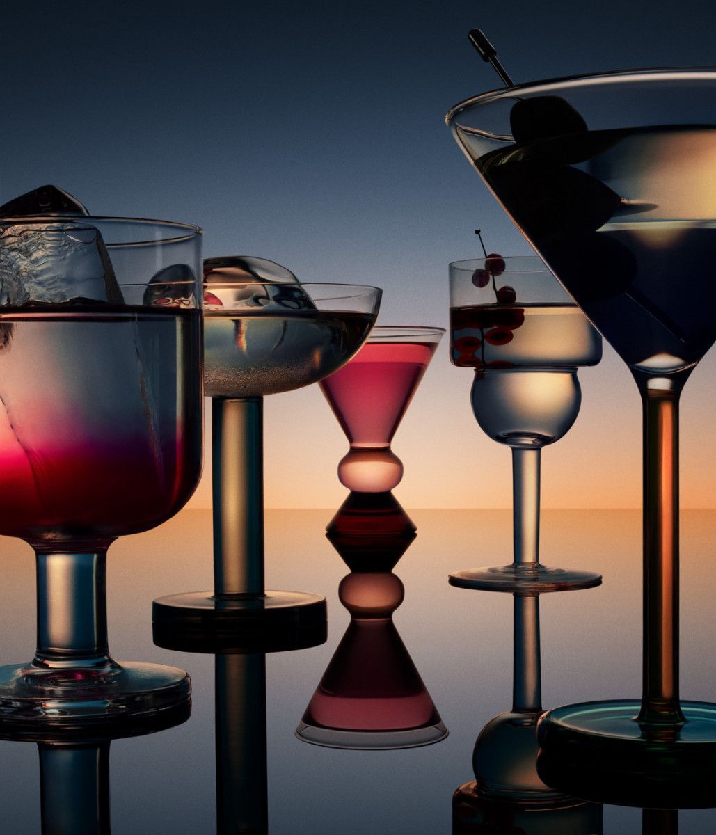 Cocktails in various glasses on a reflective surface. Purple, pink, and clear liquid. Dusk background. Food Stylist Nadine Page.