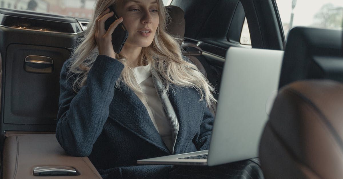 Business woman in a cab, taking a call and on her laptop