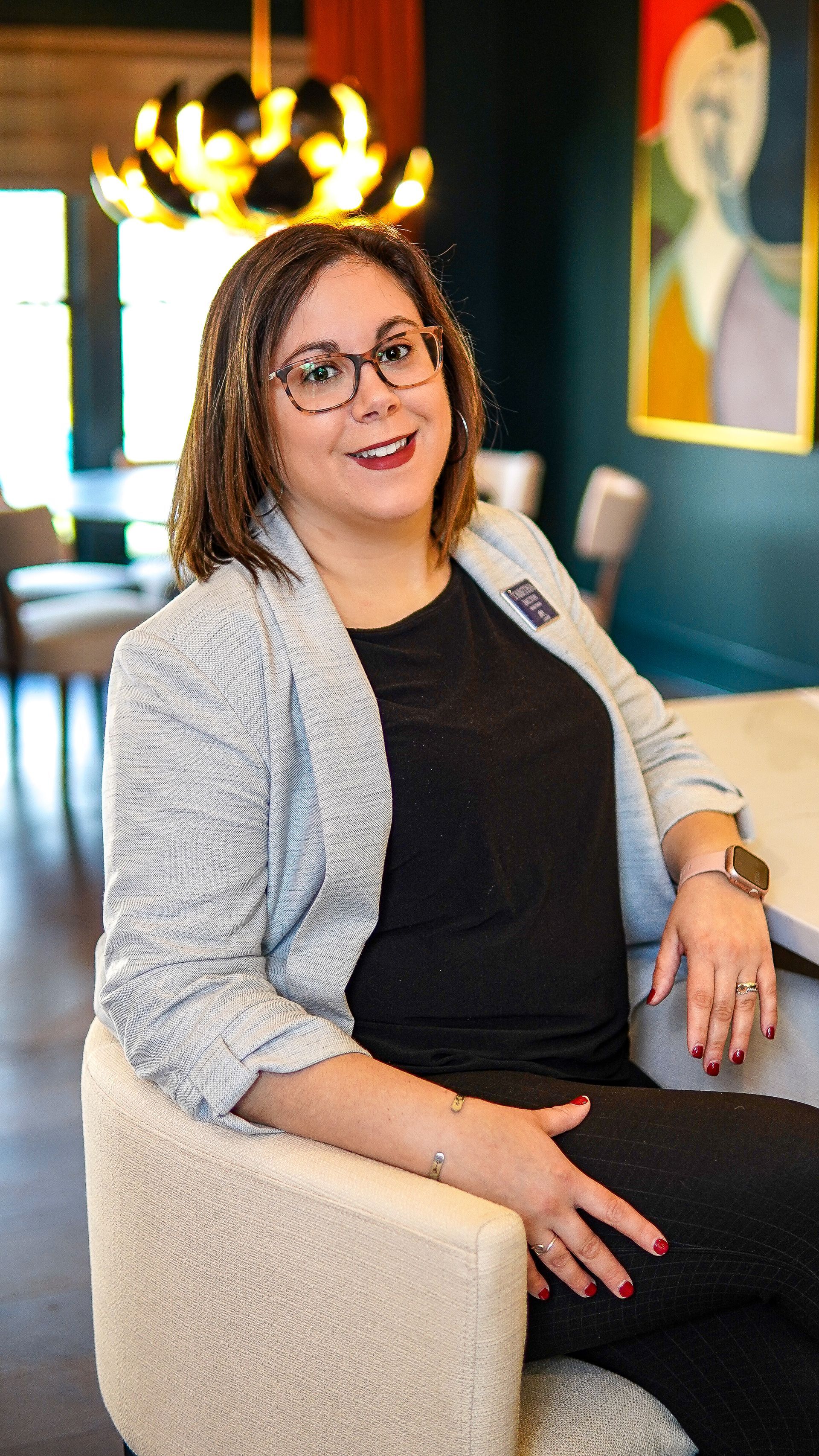 A woman is sitting at a desk with a laptop and a vase of flowers.