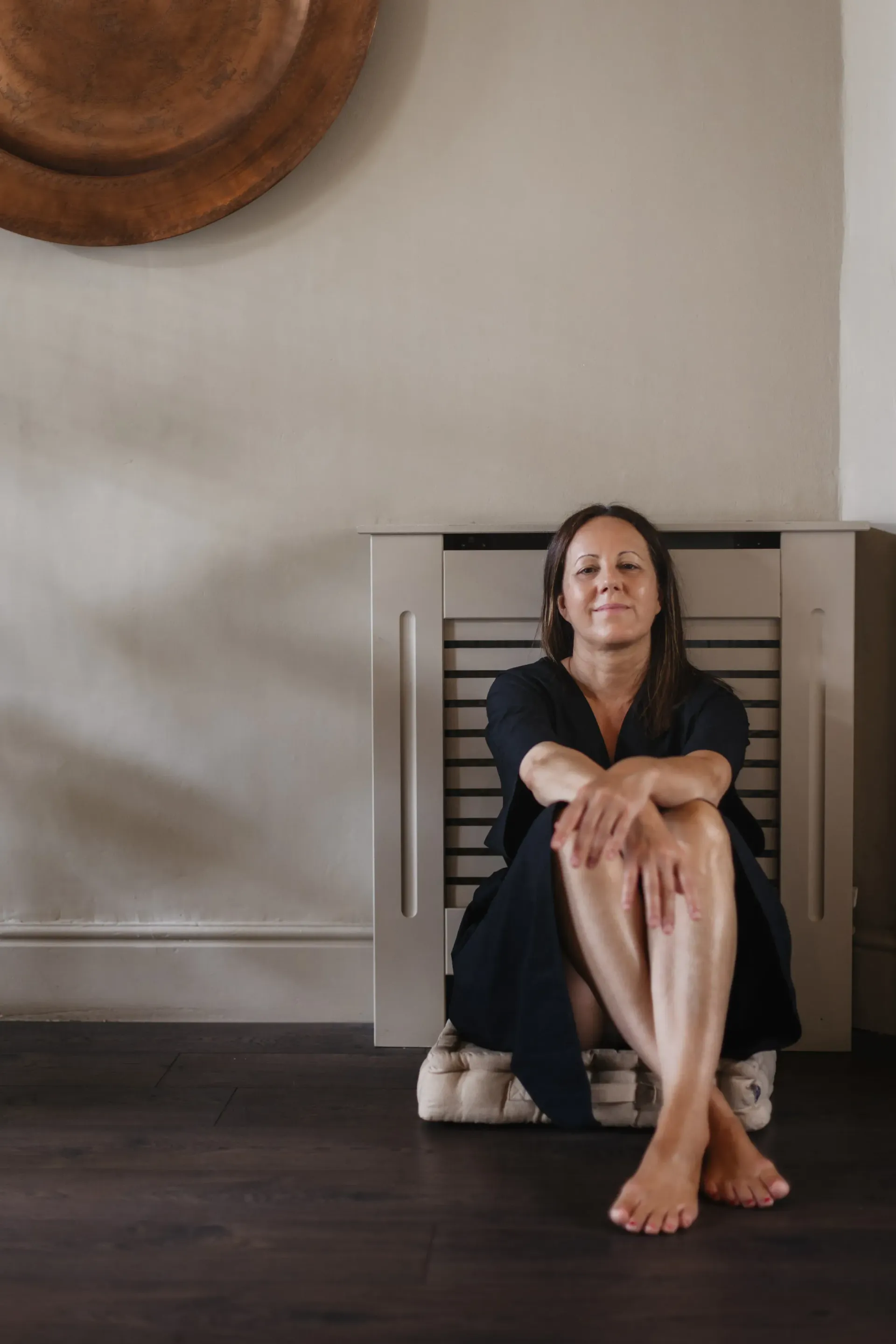 a woman sits on the floor with her legs crossed