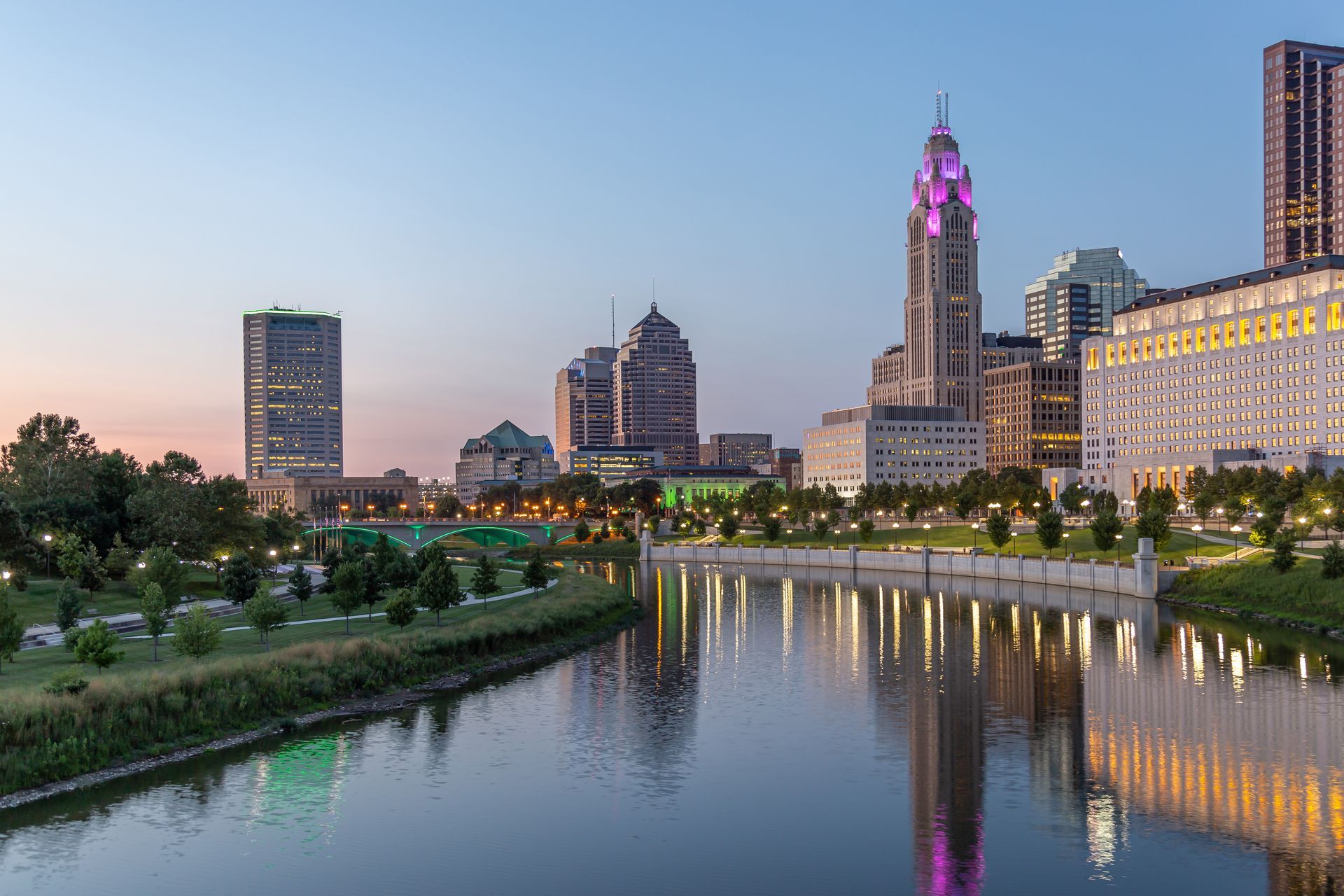 A city skyline with a river in the foreground and a clock tower in the background.