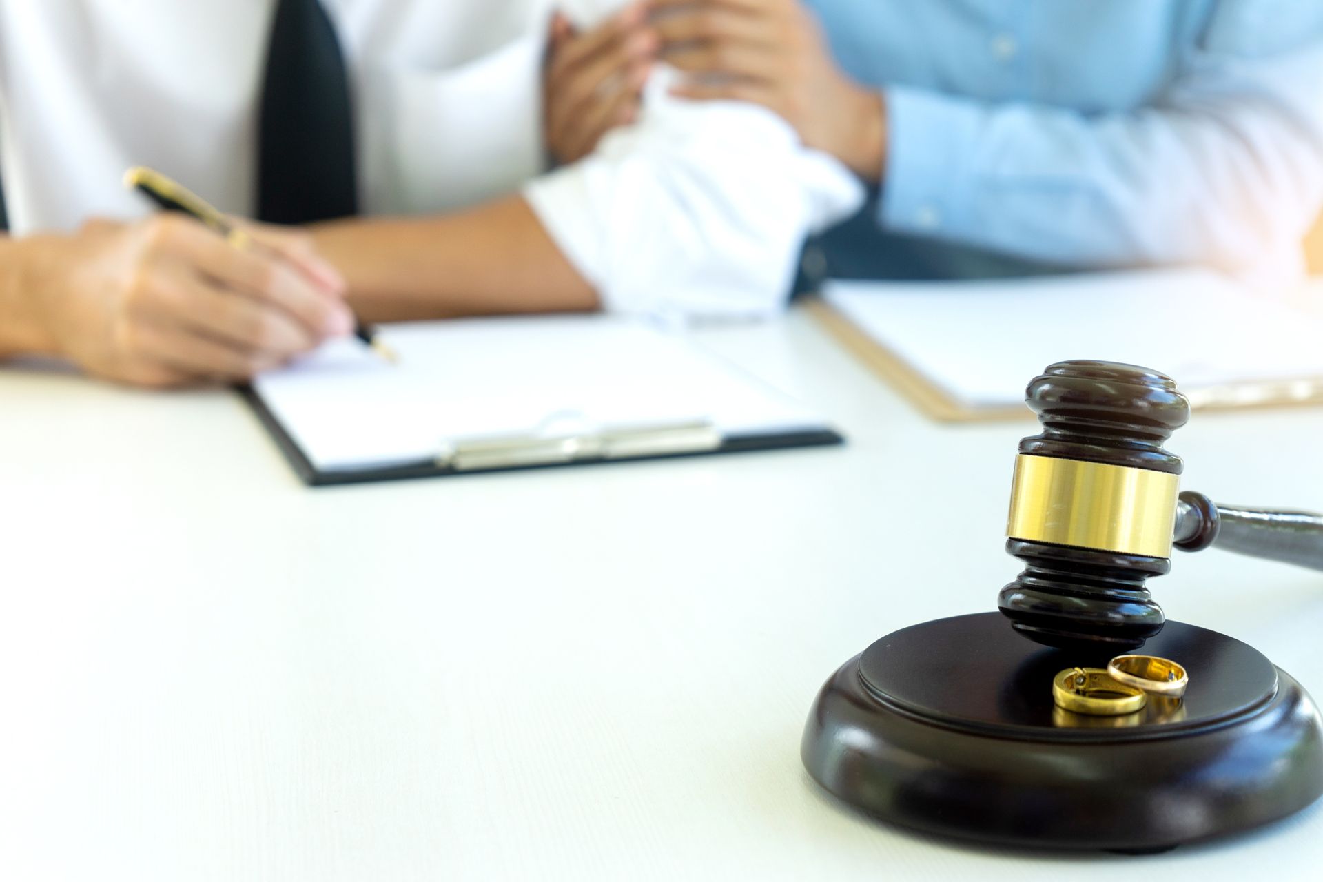 A couple is sitting at a table with a judge 's gavel and wedding rings.