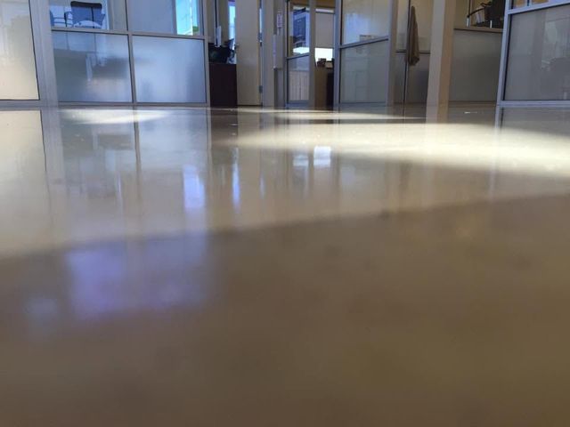 Low-angle view of a glossy hallway floor reflecting light in a quiet indoor corridor